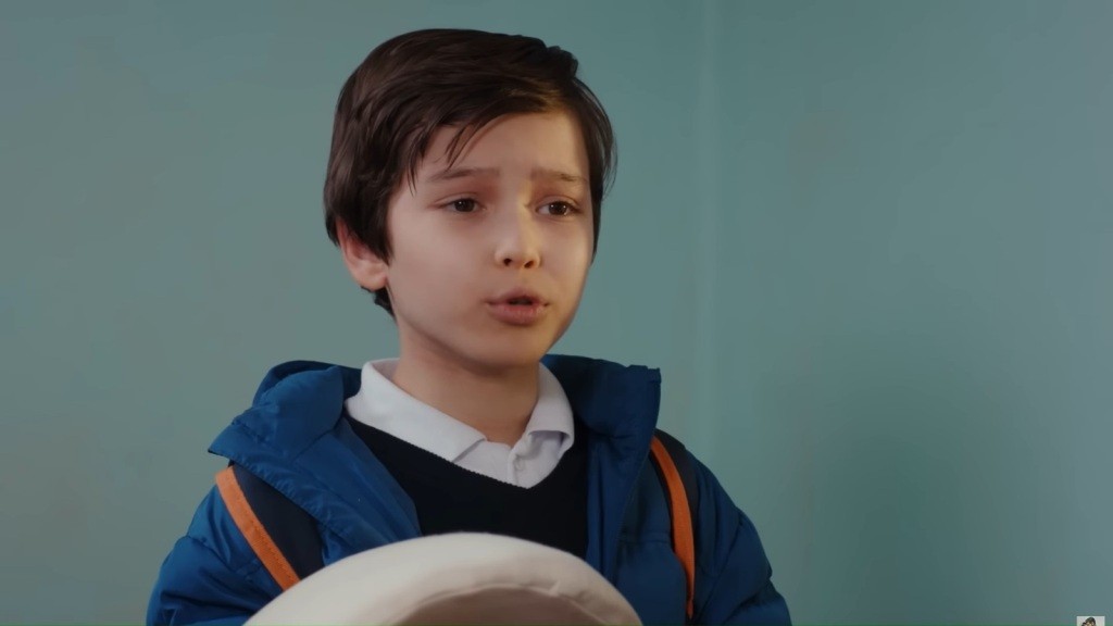Emir trzyma przed sobą sztuczny brzuch ciążowy.