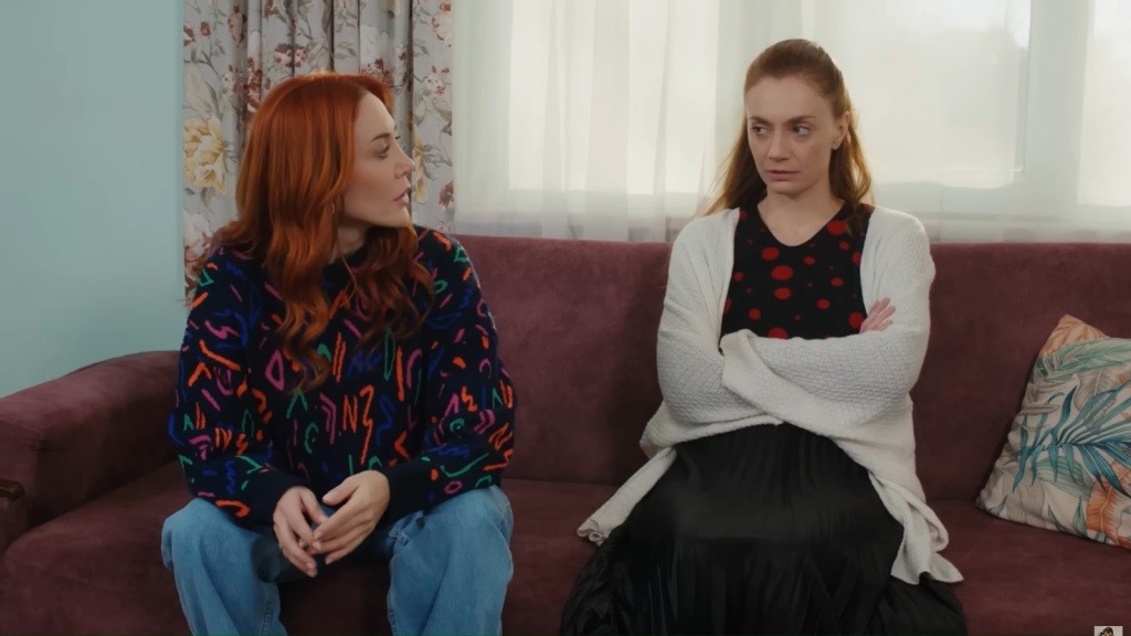 Yonca i Derya siedzą obok siebie na kanapie. Derya ma skrzyżowane ręce.