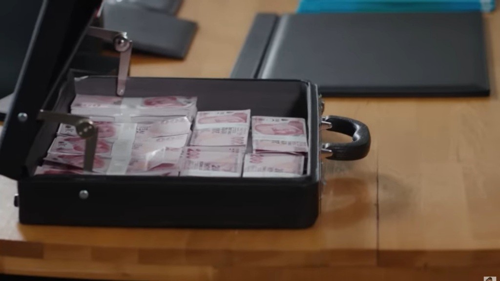 Zbliżenie na otwarty neseser z pakietami banknotów.