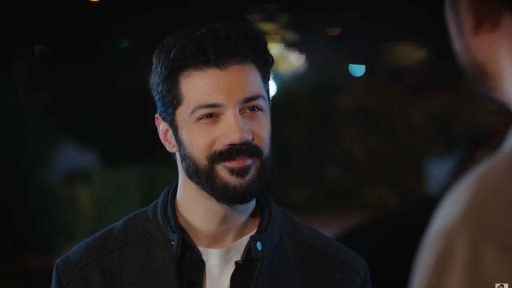 Melih uśmiecha się, patrząc w twarz Cihana. Ciemne, nocne tło.