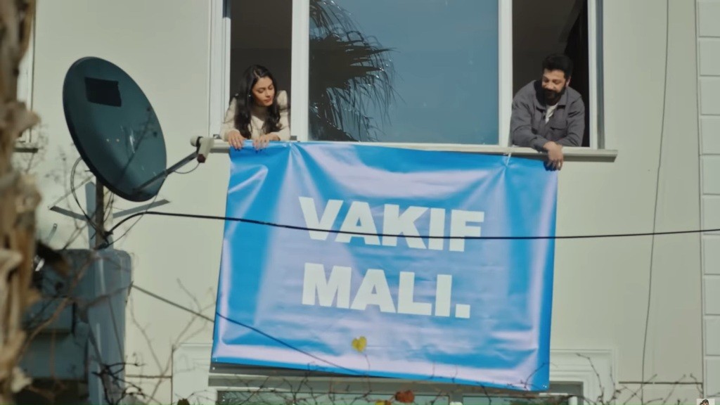 Hancer i Melih wywieszają pod oknem baner z napisem "VAKIF MALI".