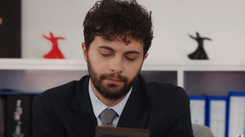 Engin siedzi wpatrzony w ramkę ze zdjęciem.