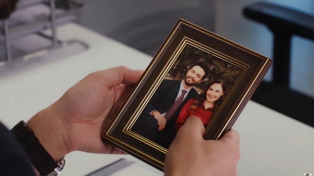 Zbliżenie na ramkę ze zdjęciem, na którym Engin i Yasemin siedzą obok siebie, oboje radośni i szczęśliwi.