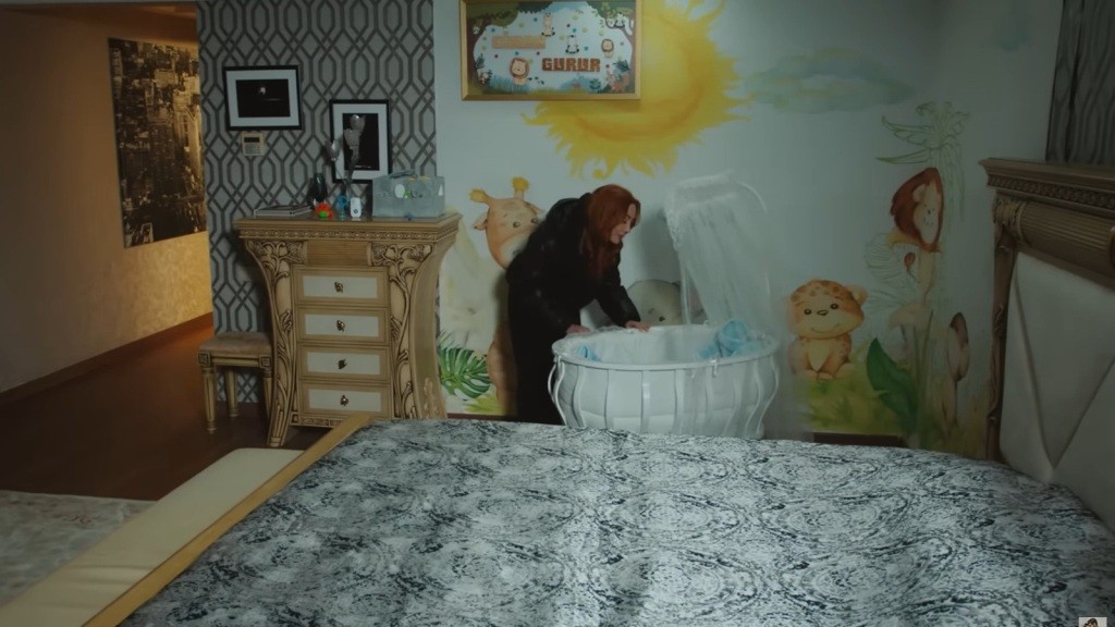 Pokój dziecięcy. Yonca pochyla się nad kołyską.