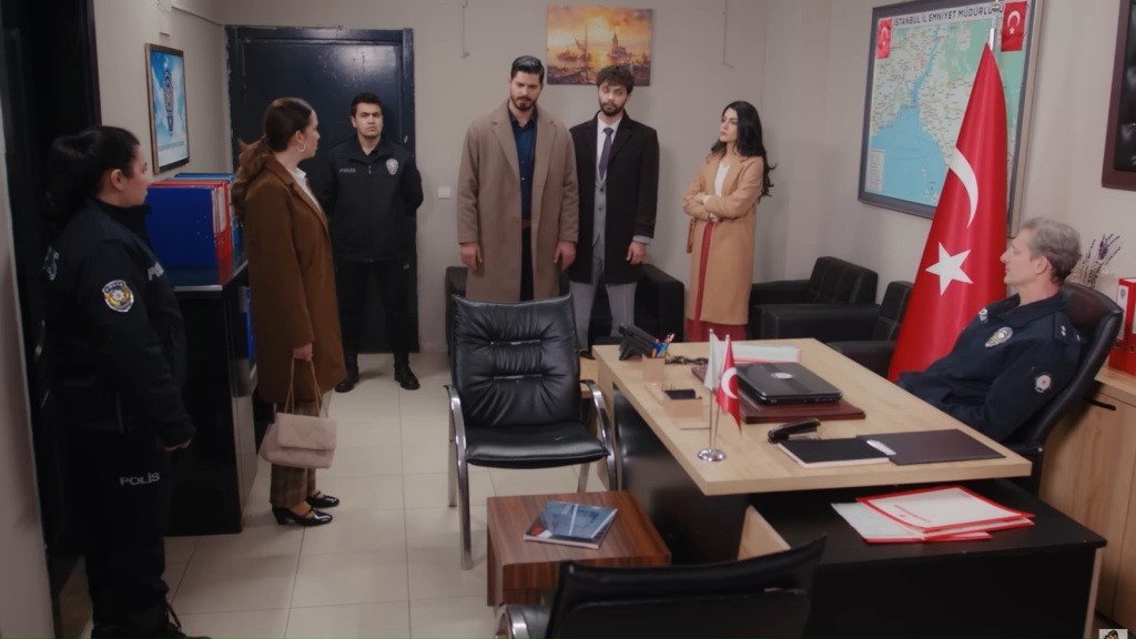 Gabinet komisarza. Komisarz siedzi za biurkiem. Cihan, Engin i Hancer stoją naprzeciwko Beyzy.