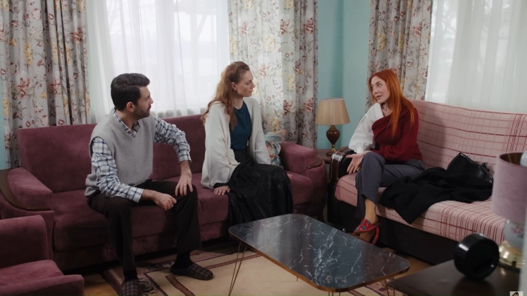 Cemil, Derya i Yonca rozmawiają, siedząc na kanapach w małym salonie.