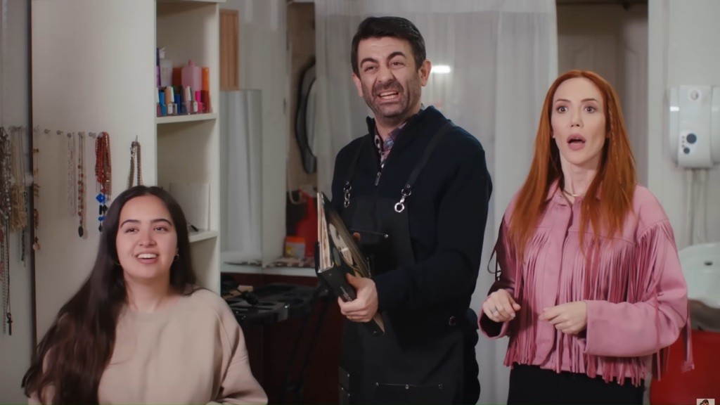 Kadr w salonie fryzjerskim. Klientka siedzi, a obok niej stoją Cemil i Yonca.